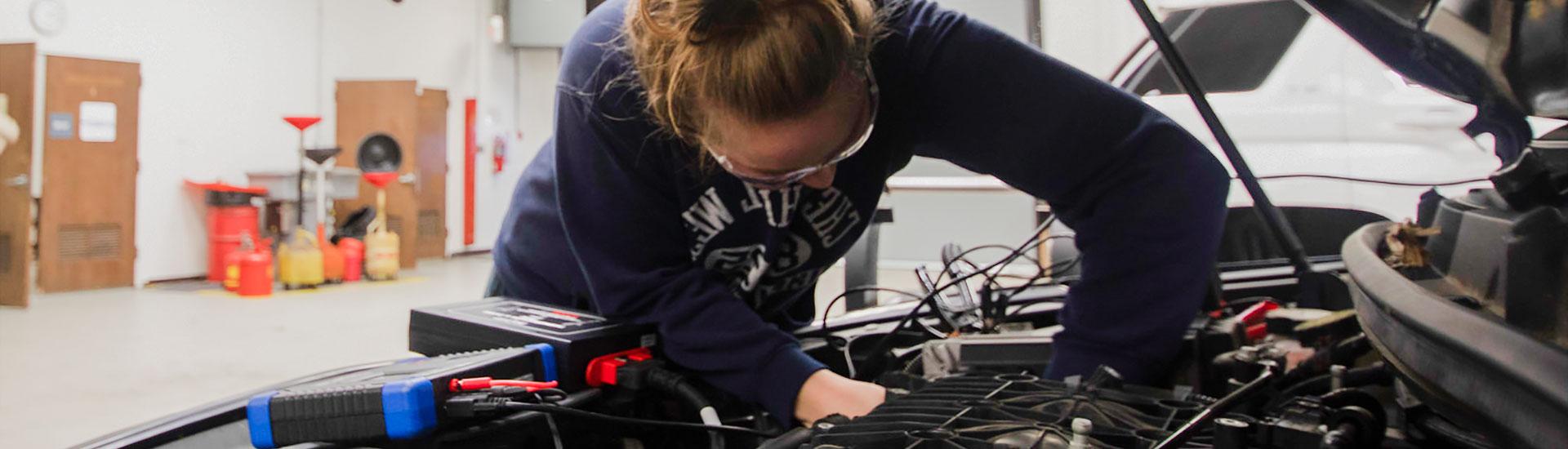 young women working on the engine of a car